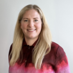 Leende kvinna med ljus långt hår och färgglad tröja.