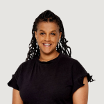 Porträtt av en kvinna med mörkt lockigt hår, klädd i en svart topp, leende mot kameran.