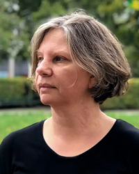 Profilbild på Maria Wemme. Maria står vänd i profil, gråbrunt hår i oage och en svart tröja. 