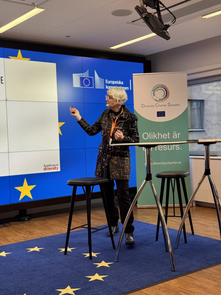 Kvinna med grått hår står och pekar på en skärm.