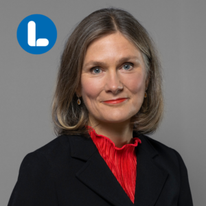 Kvinna i mellanlångt mörkblont hår och röd tröja med svart kavaj över.
