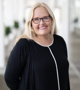 Pernilla Glad ler mot kameran, med blont hår och glasögon.